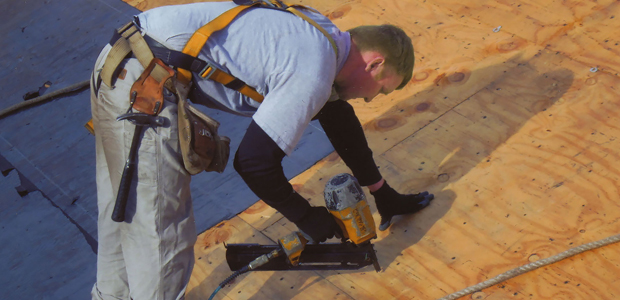 Older man on a roof installing shingles